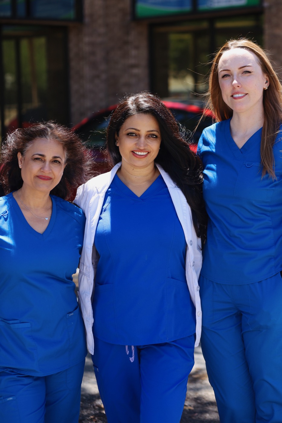 Dr. Bhatti and two team members smiling outside the office building